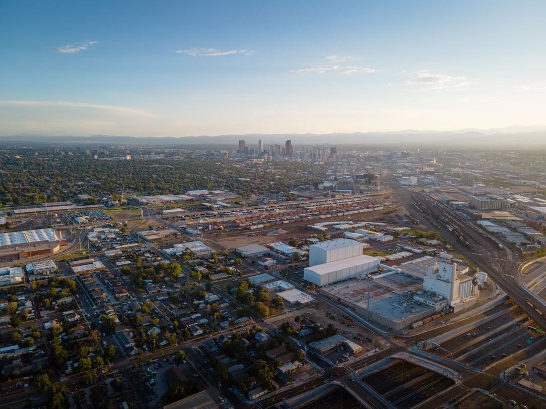 Aerial view of Denver at dusk with residential blocks in the foreground and the downtown skyline and Front Range beyond