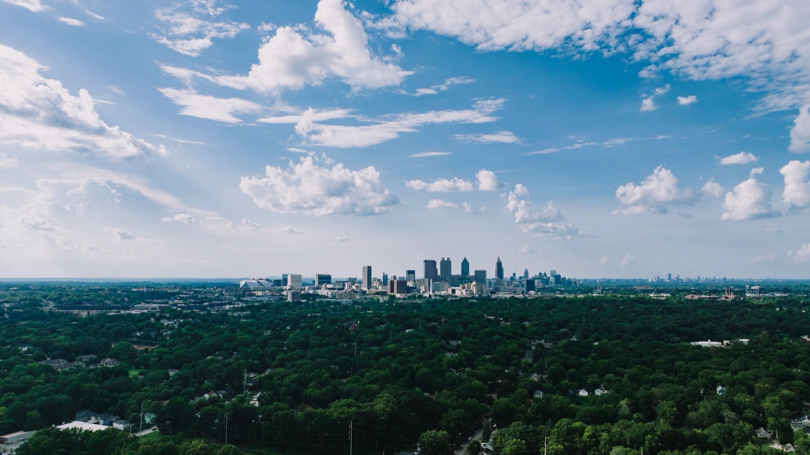 Aerial view of the Atlanta, Georgia skyline rising above tree-covered residential neighborhoods
