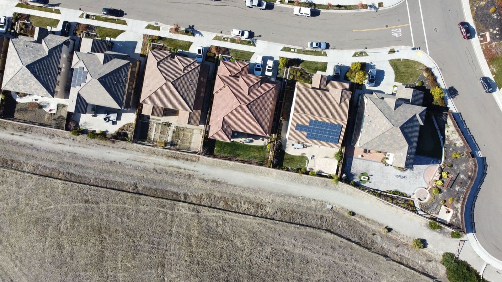Overhead view of a California suburban street with rooftop solar panels on two homes