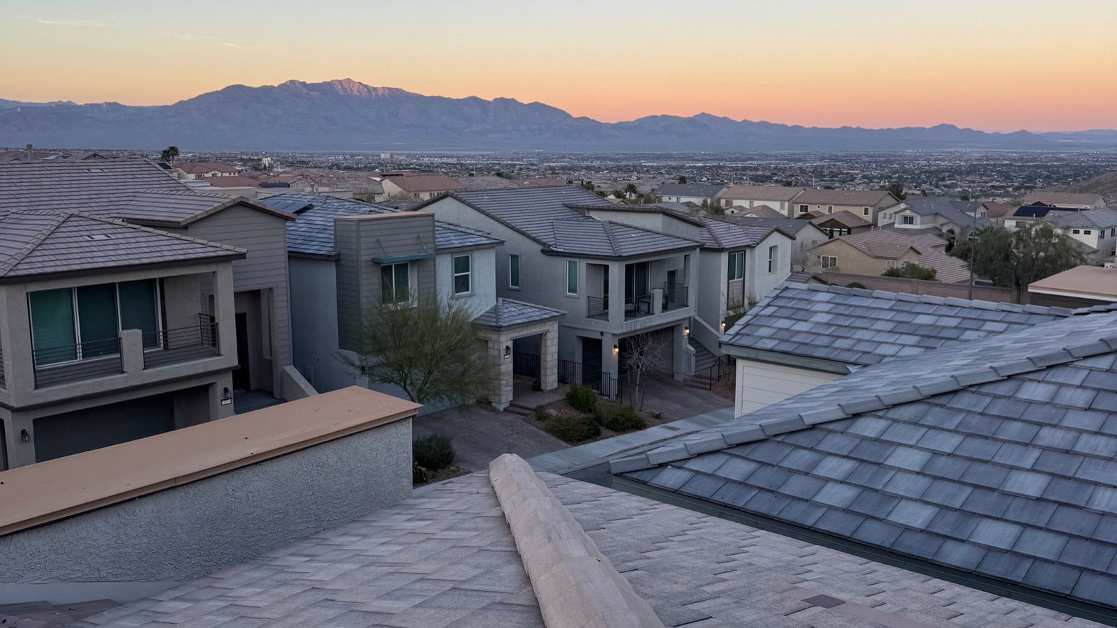 Suburban homes with tiled roofs at twilight in Las Vegas, Nevada, with mountains in the distance